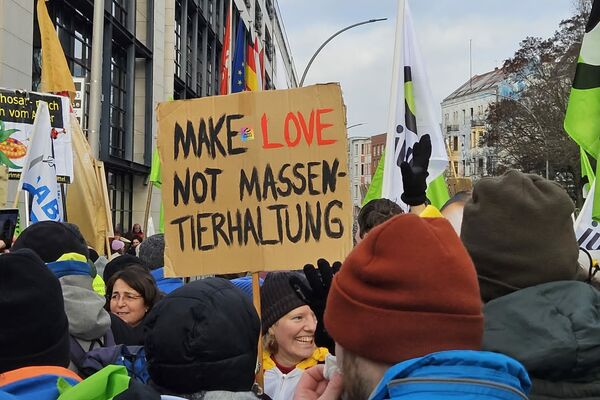 Eine Gruppe Menschen mit einem Plakat "Make love, not Massentierhaltung".