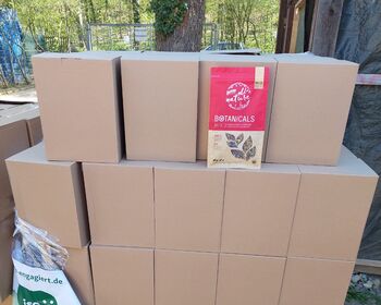Eine Palette mit gestapelten Kartons, eine Beutel mit getrockneten Kaninchenkräutern zur Ansicht.