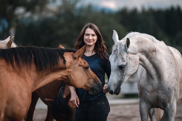 Eine junge Frau inmitten von braunen und weißen Pferden.