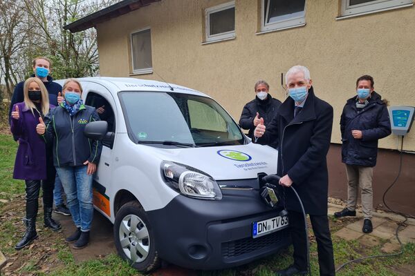 Die Sponsoren und Unterstützer stehen rund um den weißen, mit Reklame und Tiermotiven bedruckten Kleintransporter.