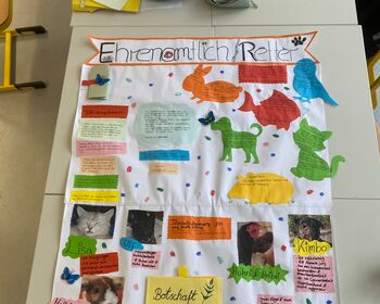 Ein großes weißes Plakat mit verschiedenfarbigen Textfeldern und Tiermotiven.