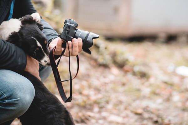 Ein Fotograf spielt mit einem Hundewelpen, der versucht, an die Kamera zu gelangen.